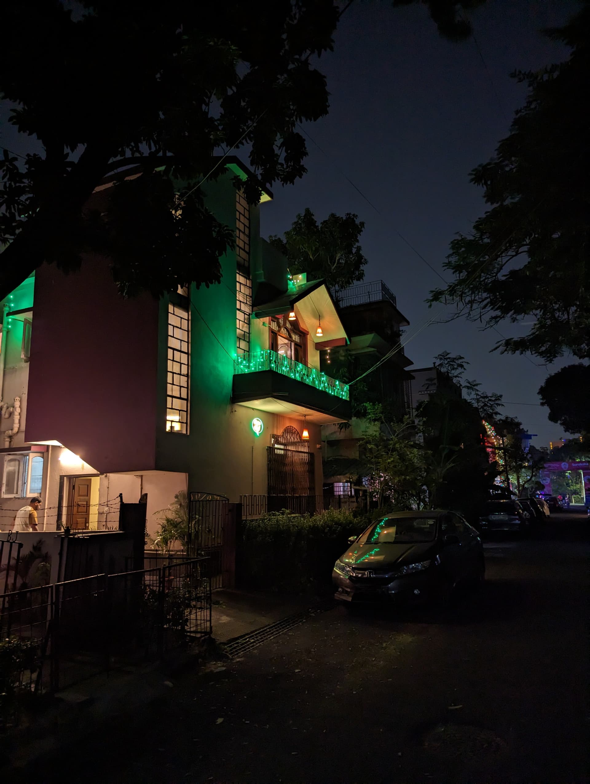 Vertical exterior night shot of Guten Tag Kolkata villa decorated with green fairy lights against the night sky