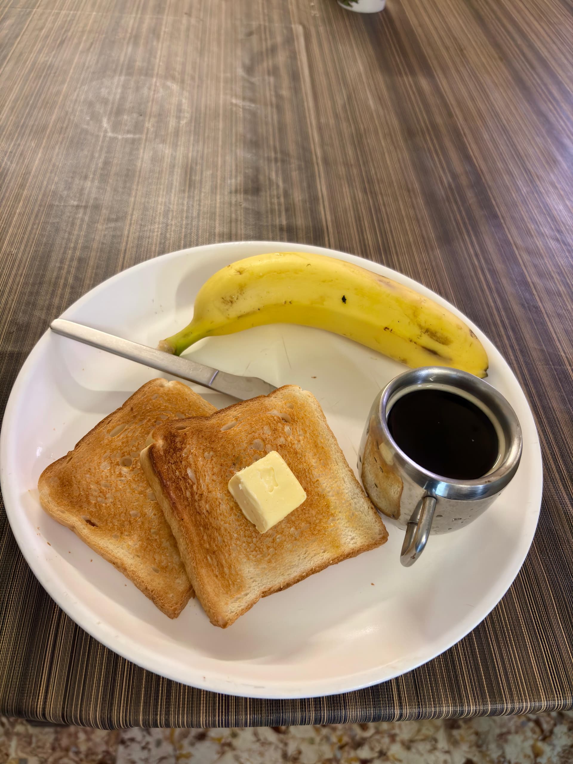 Fresh morning breakfast plate with toasted bread, butter, banana, and hot beverage served at Guten Tag Kolkata