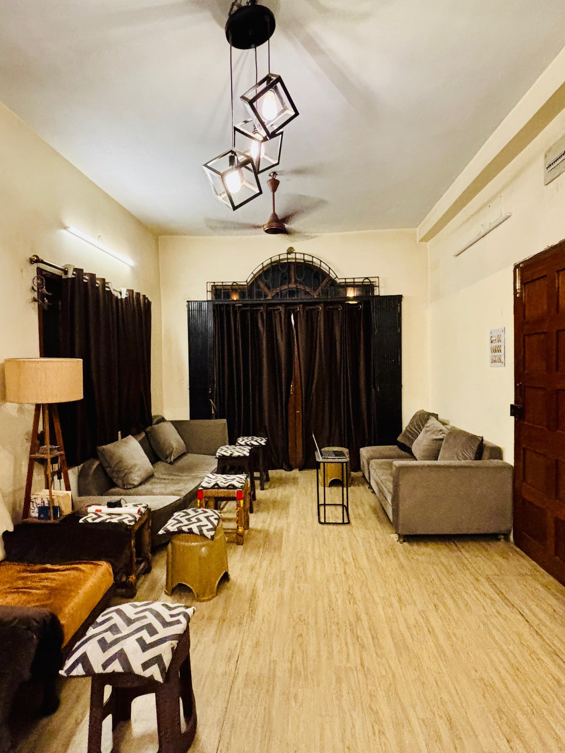 Common lounge interior with geometric pendant lighting fixtures, comfortable couches, and patterned seating stools