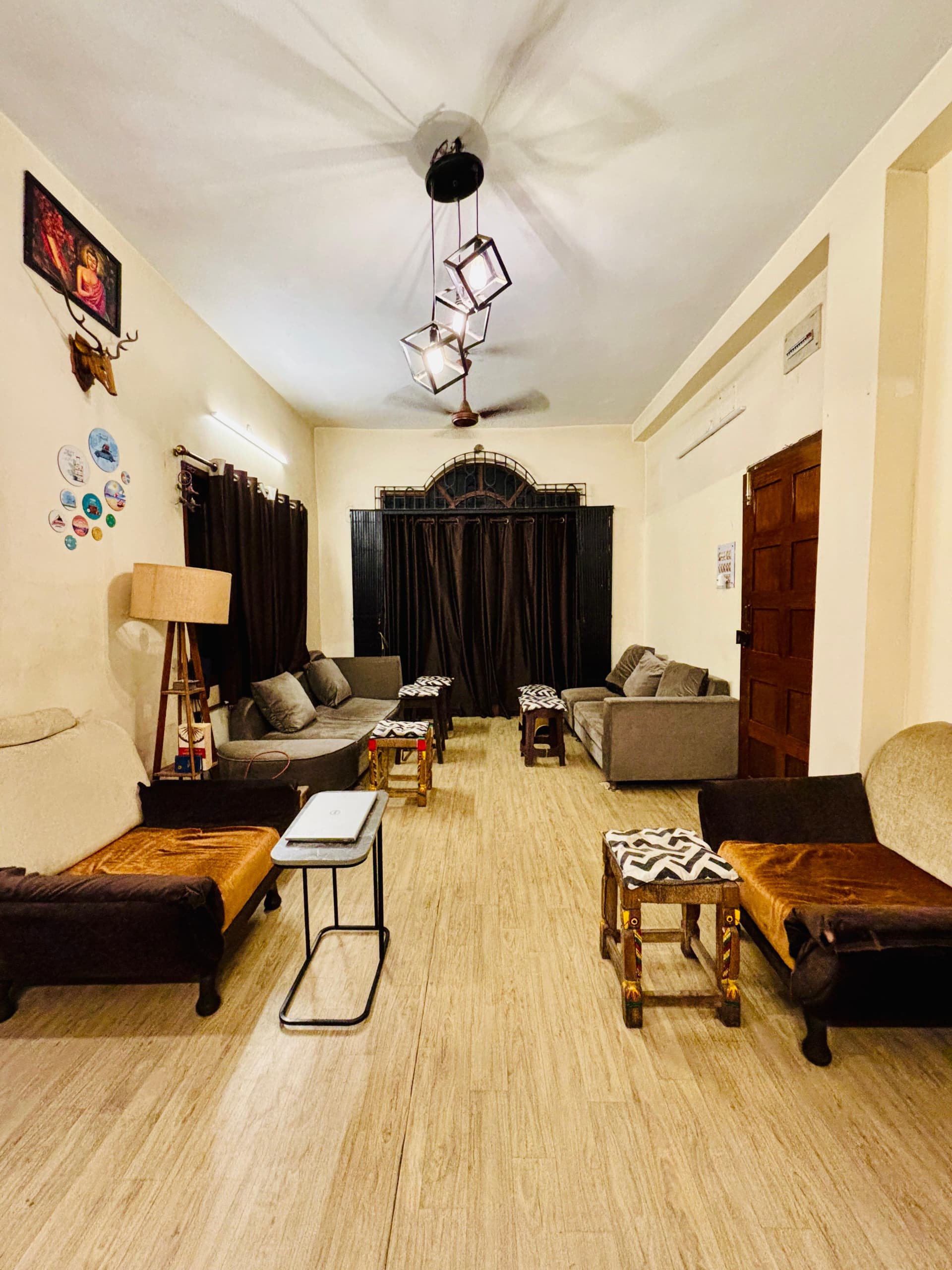 Full view of Guten Tag Kolkata common lounge with armchairs, laptop table, side stools, and ambient lighting