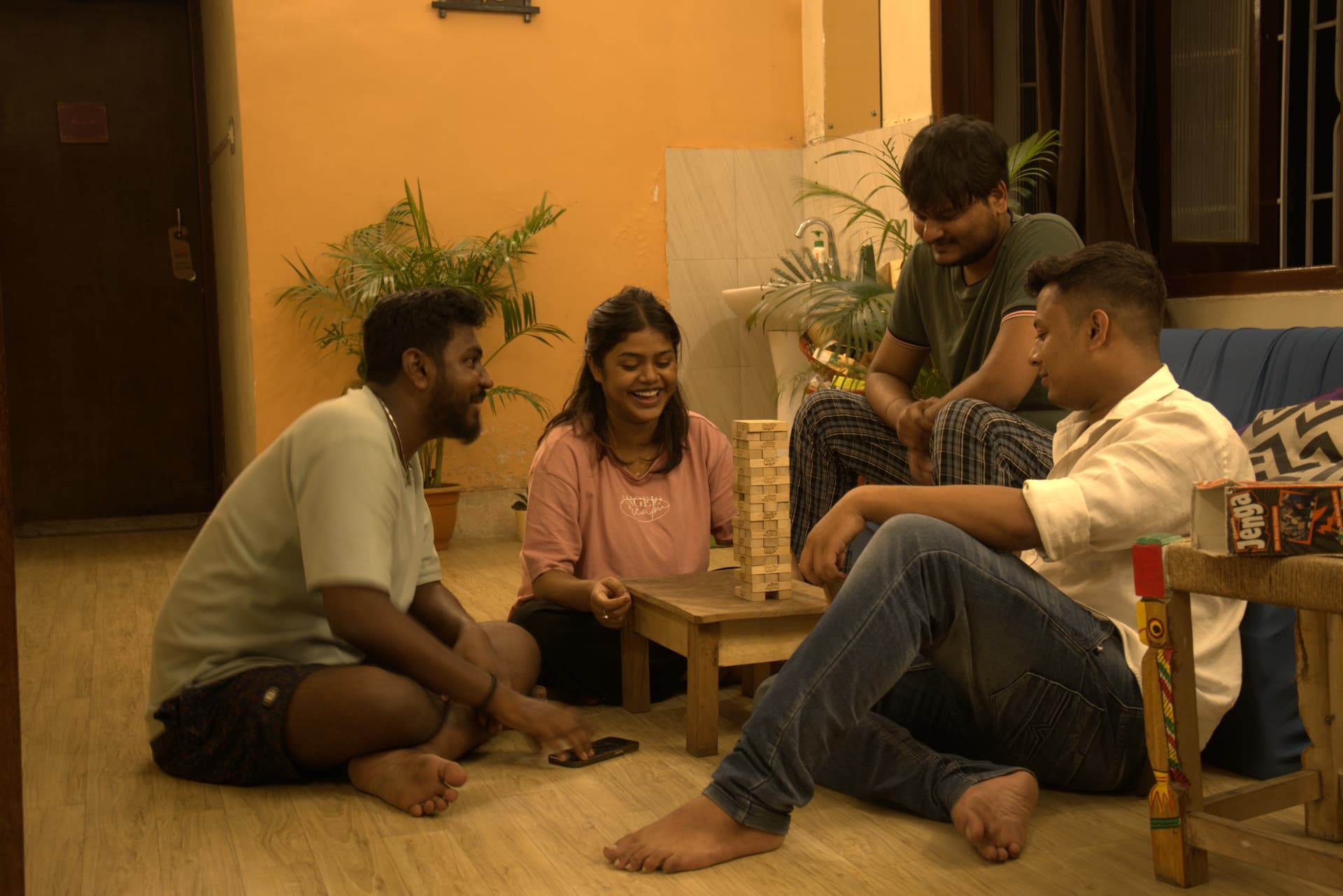 Backpackers enjoying a tabletop Jenga game during an evening social in the common room