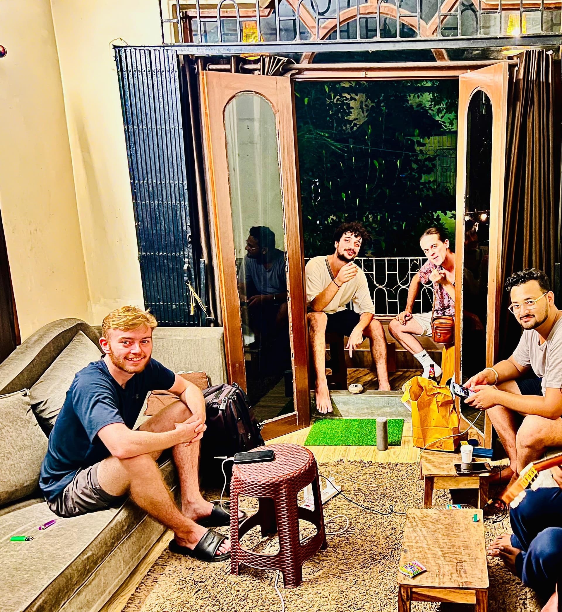 Hostel guests and international travelers relaxing together in the lounge and balcony in the evening